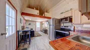 A spacious kitchen with wooden cabinets, a stainless steel refrigerator, an oven, and a wooden countertop.