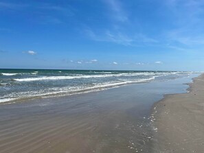 A beach with a wide sandy shore and gentle waves.