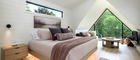 Un dormitorio con cama, mesita de noche y un ventanal amplio.