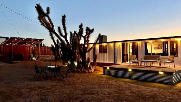 Una casa moderna con patio, mobiliario exterior y cactus.