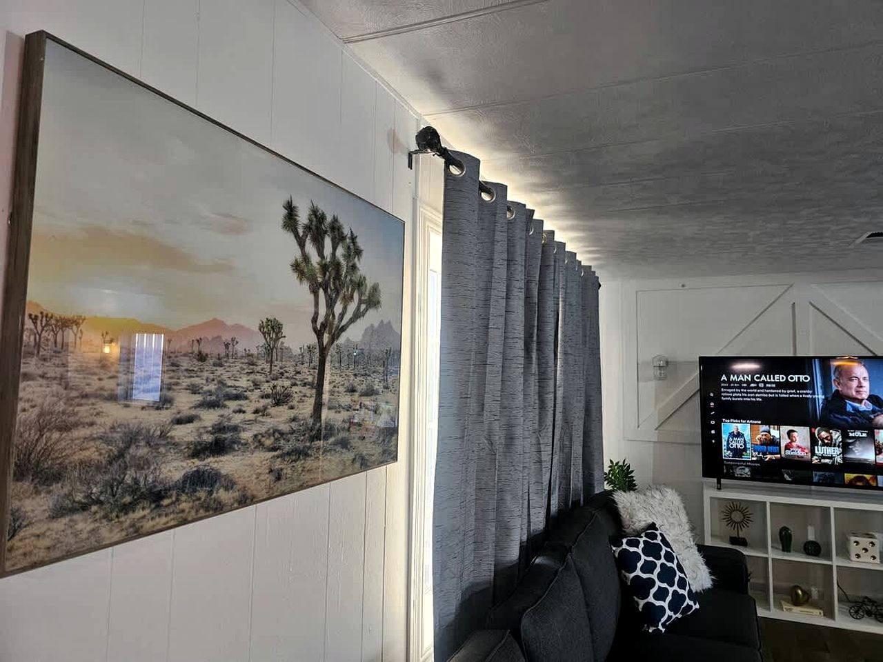 Een woonkamer met een groot schilderij, een televisie en een bank.