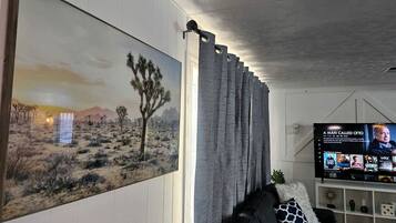 Een woonkamer met een groot schilderij, een televisie en een bank.