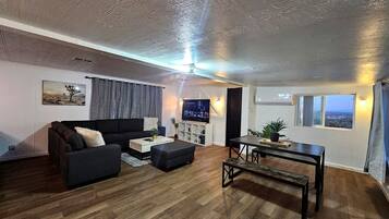 Una sala de estar con sofá, mesa de centro y televisión.