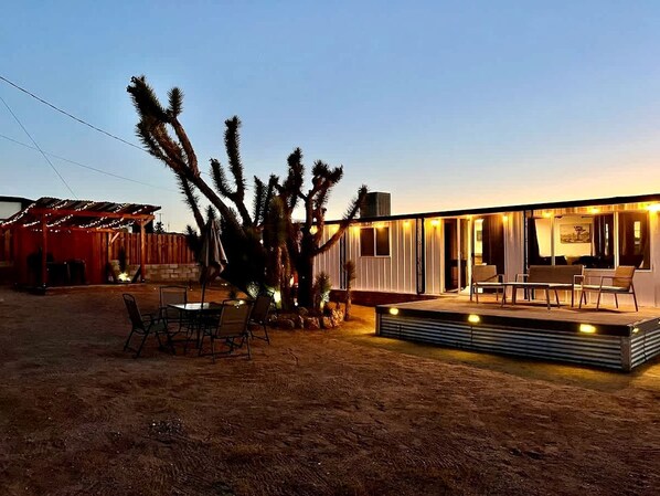 A modern house with a patio, outdoor seating, and cacti.