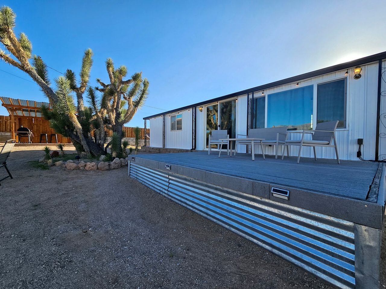 A modern building with a covered patio area, outdoor seating, and a cactus plant.