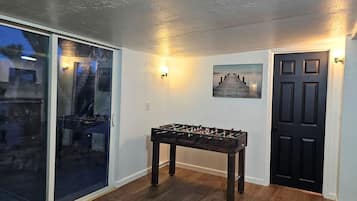 Une pièce avec une table de baby-foot, une porte et un tableau au mur.