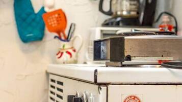 Een keuken met een vintage fornuis, een koffiezetapparaat en diverse keukengerei.
