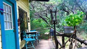 A wooden deck with a table and chairs, a blue door, and a hanging plant.