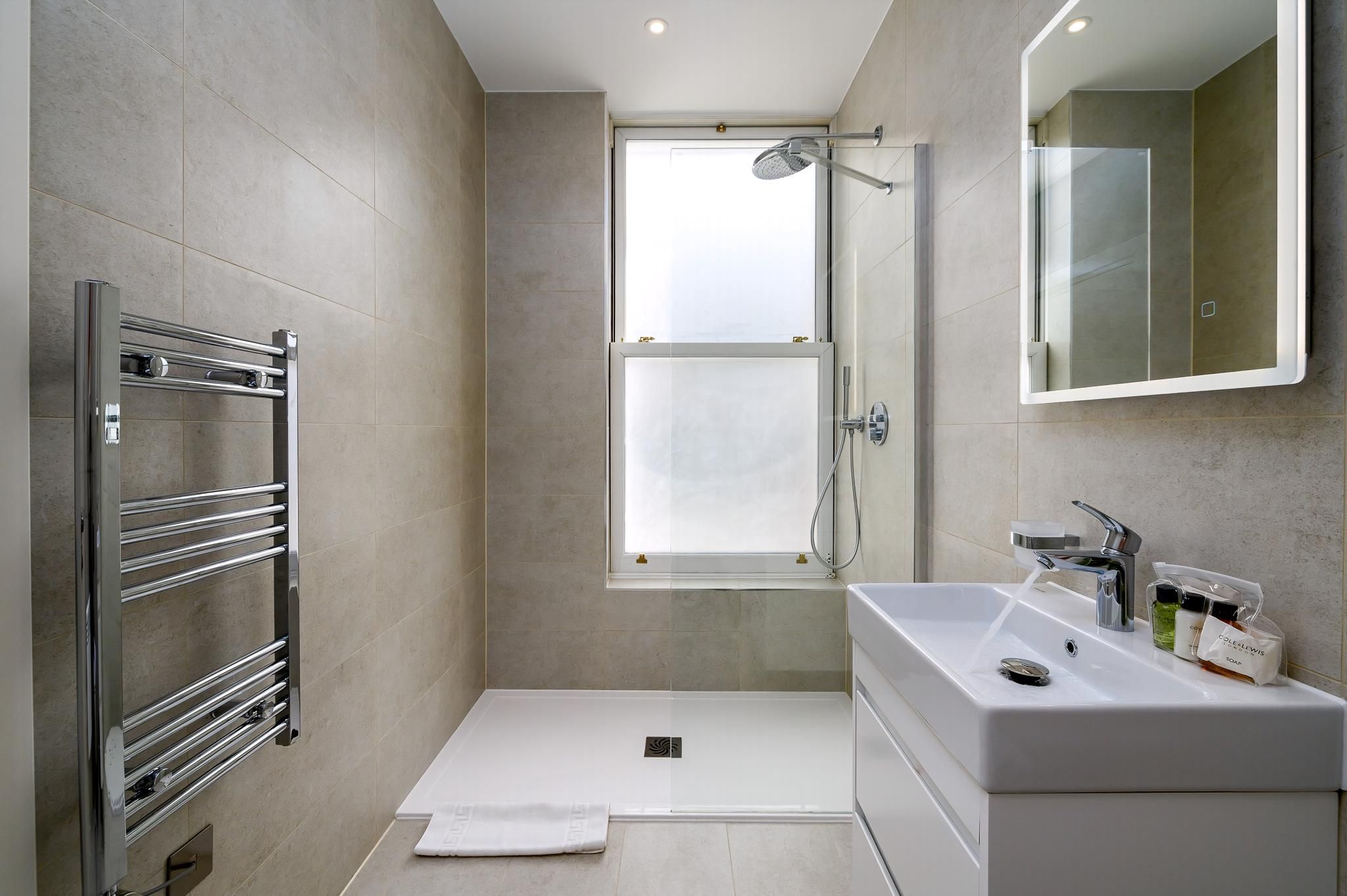 A modern bathroom with a walk-in shower, a built-in sink, and a towel rack.