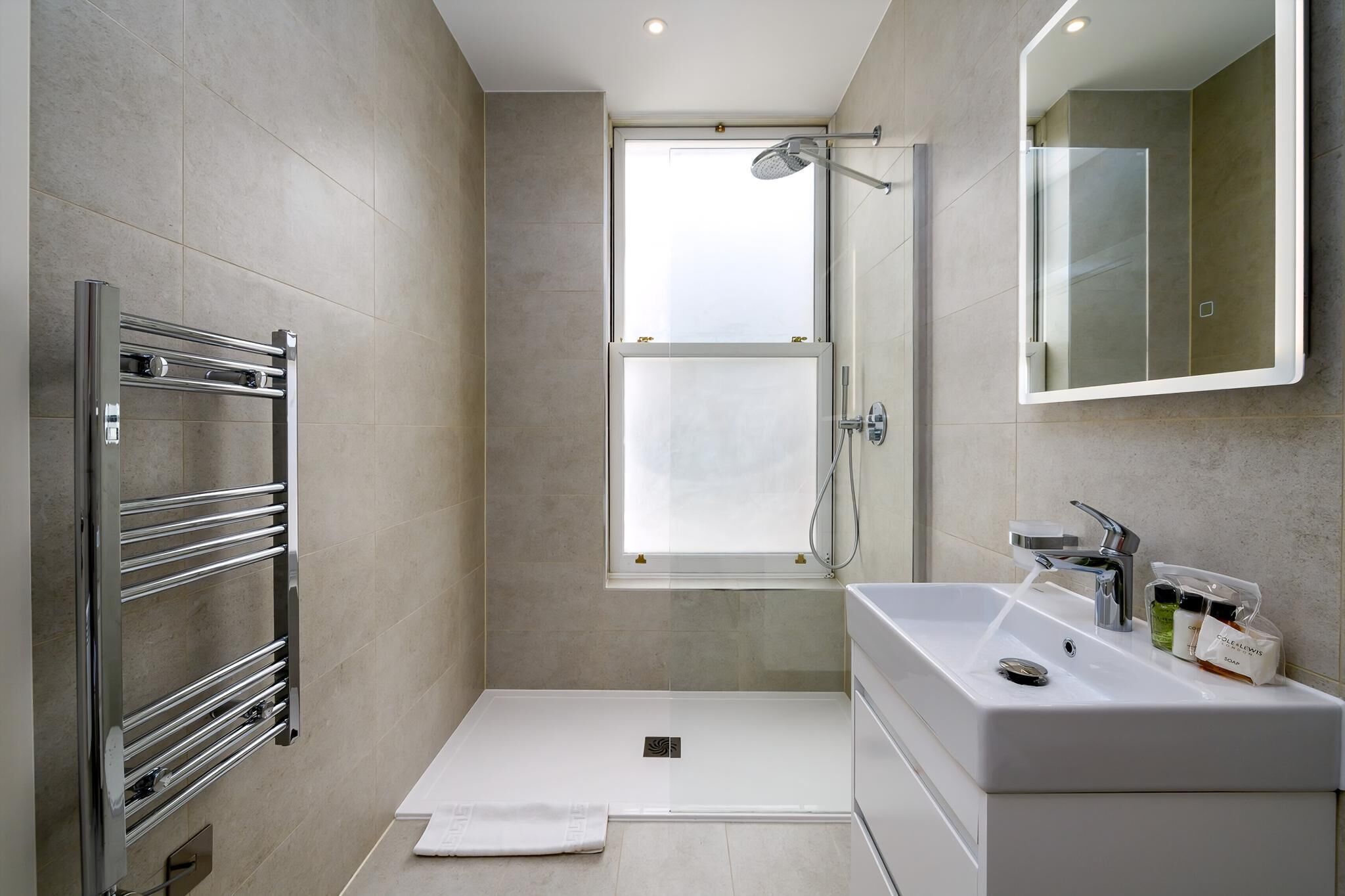 Une salle de bain moderne dotée d’une douche à l’italienne, d’un lavabo intégré et d’un porte-serviettes.