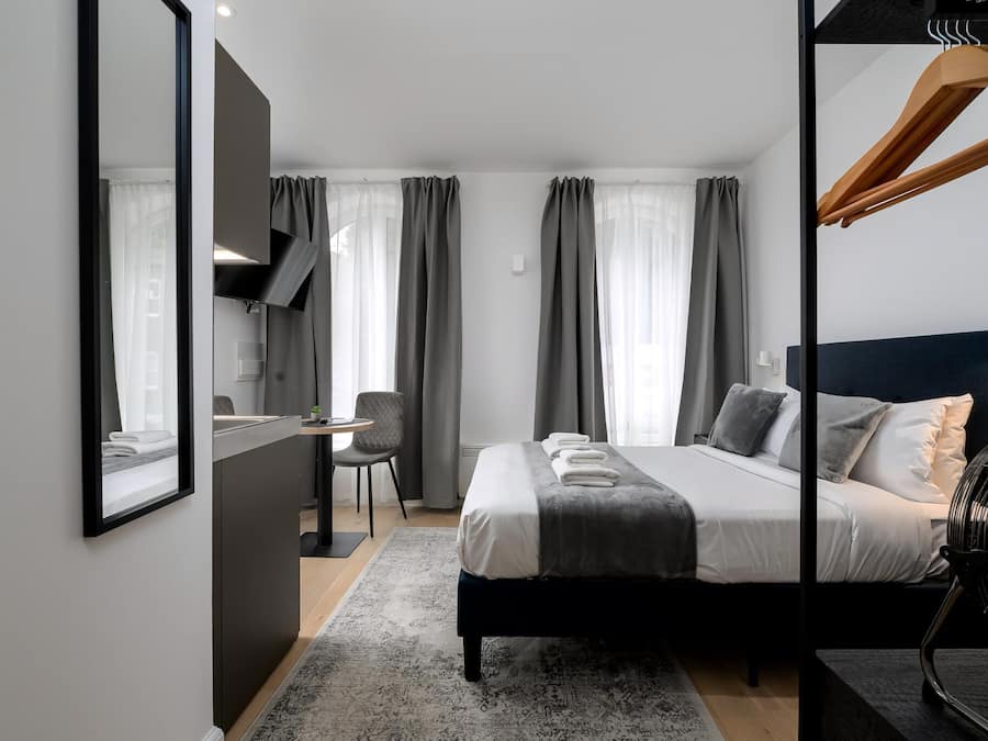 Una habitación de hotel moderna con una cama grande, un escritorio y una silla.