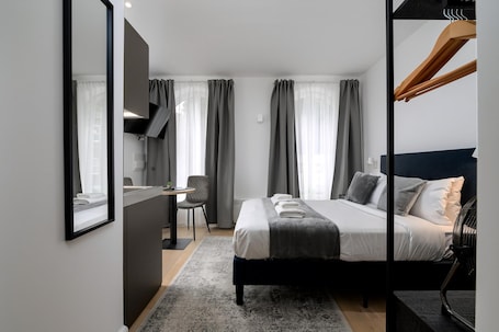 A modern hotel room with a large bed, a desk, and a chair.