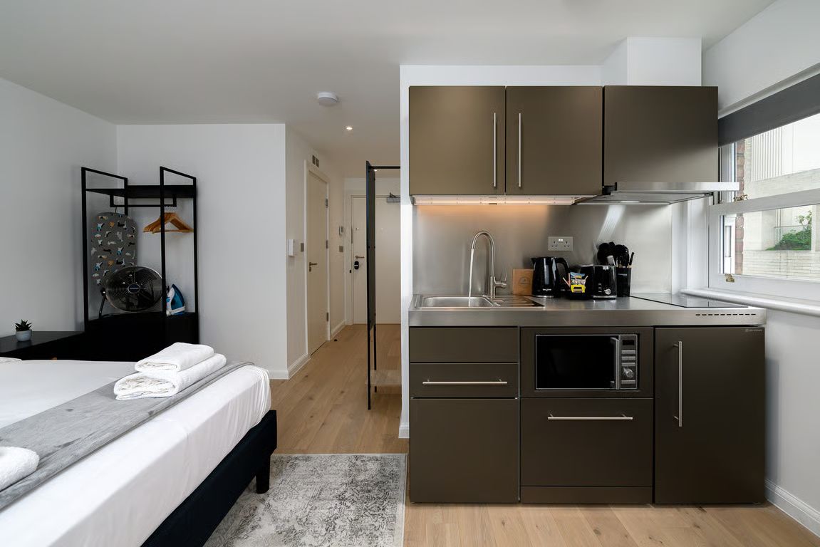 A modern kitchen with stainless steel appliances, a built-in oven, and a window overlooking the street.
