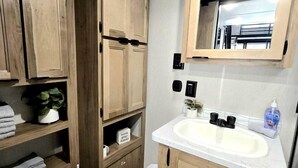 A bathroom with a toilet, wooden cabinets, a sink, and a mirror.