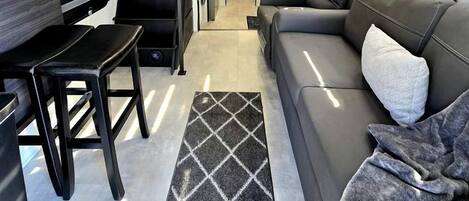Un espacio habitable compacto con un sofá, una mesa de comedor y una escalera que sube a un nivel superior.