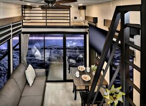 A modern interior with a sofa, dining table, and a staircase.
