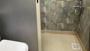 A small, enclosed shower area with a glass door, tiled walls, and a toilet visible to the left. - Weekend Hotel (Beirut)