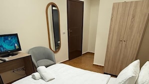 Ein Hotelzimmer mit Bett, Schreibtisch mit Computer, Stuhl, Kleiderschrank und Tür.