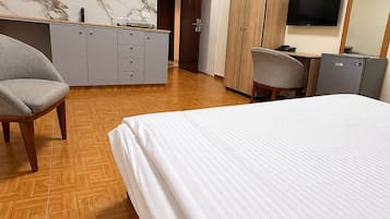 A hotel room with a bed, a desk, a chair, a wardrobe, and a television.