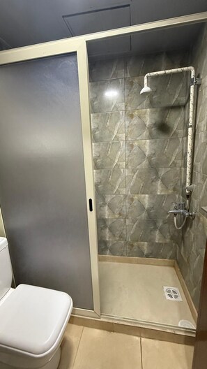 A small, enclosed shower area with a tiled wall and a showerhead. - Weekend Hotel (Beirut)