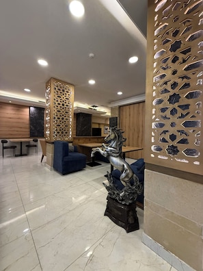 A modern interior with a marble floor, a blue sofa, a decorative horse statue, and a wooden partition with geometric cutouts. - Weekend Hotel (Beirut)