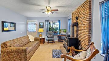 A living room with a sofa, a chair, a table with a lamp, a television, and a fireplace.