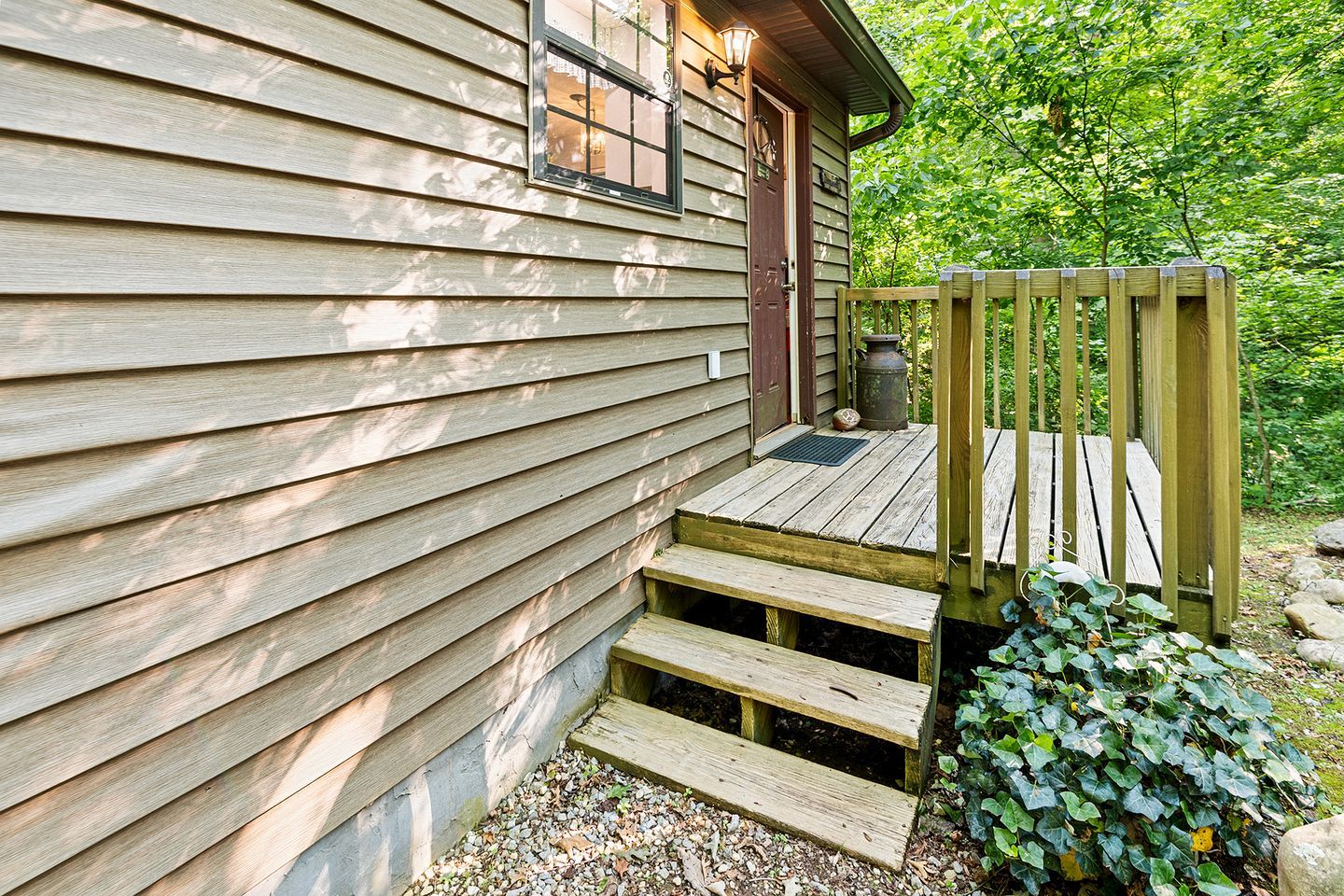 A wooden cabin with a porch, steps, and a small garden area.