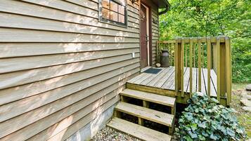 A wooden cabin with a porch, steps, and a small garden area.