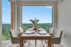 Une table à manger dressée pour deux personnes, avec vue sur une forêt et un plan d’eau.