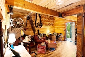 Un interior rústico de madera con zona de comedor, sillas de cuero, una mesa con lámpara y un carrusel grande.