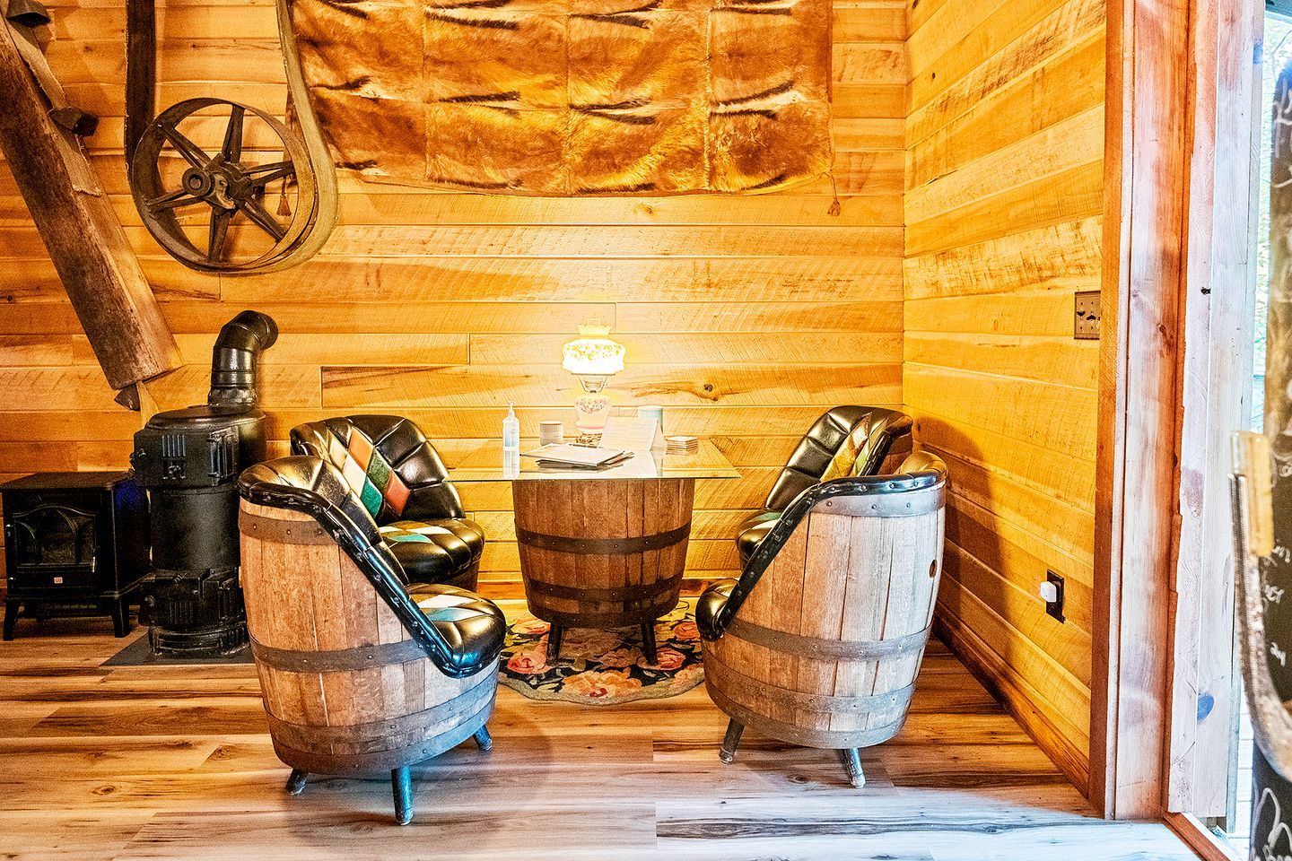 L’intérieur d’un chalet confortable, avec deux fauteuils en cuir, une table, une lampe et un poêle à bois.