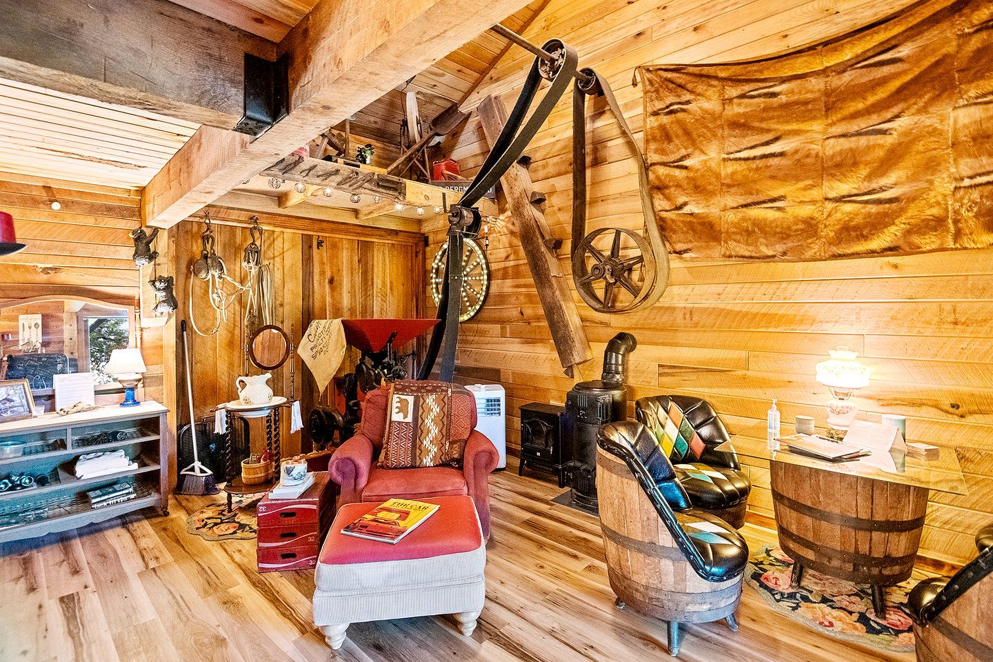 Un intérieur rustique avec des éléments en bois, notamment un fauteuil rouge, un poêle d’époque et un plafond en bois.