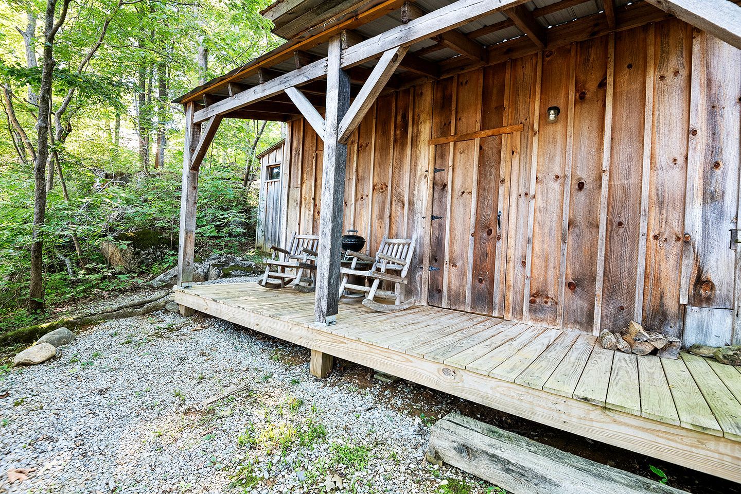 Eine Holzhütte mit Veranda, zwei Schaukelstühlen und einer Leiter.