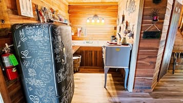 Une cuisine chaleureuse avec des murs en bois, un réfrigérateur orné de messages écrits à la main et un évier.