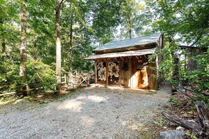 A rustic wooden cabin with a gravel path leading to it, surrounded by dense forest. - Luxury Cabin for Two with Beautiful River Views near Knoxville (Greeneville)