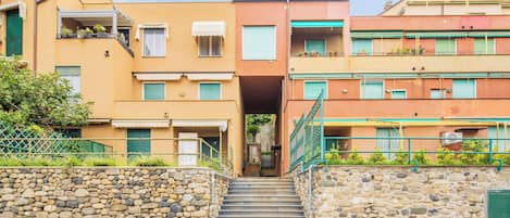 Un immeuble à plusieurs étages, avec un escalier en pierre menant à l’entrée.