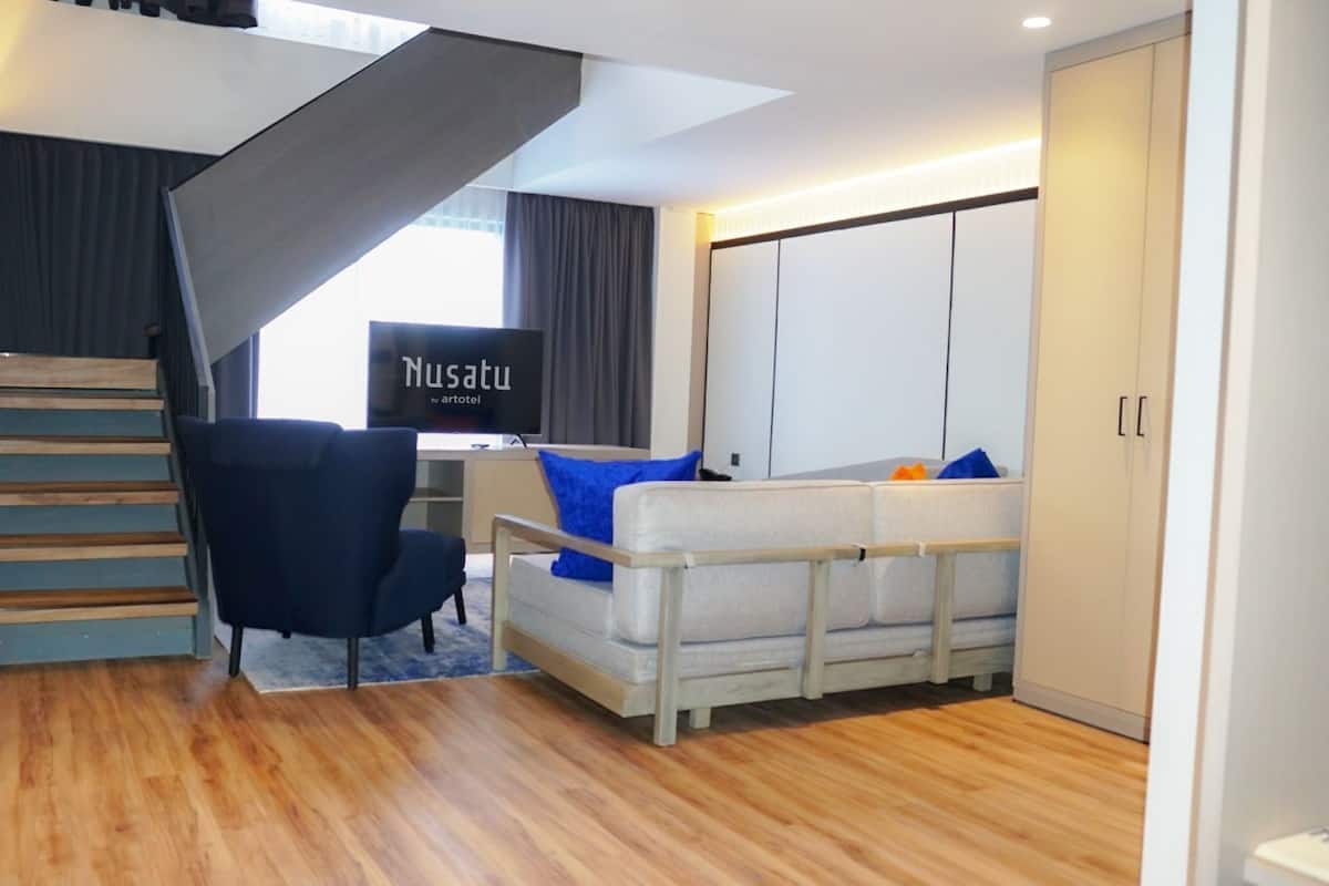 A modern living room with a staircase, a sofa, a chair, and a TV.
