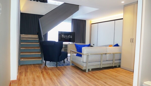 A modern living room with a staircase, a sofa, a chair, and a TV. - Nusatu by ARTOTEL - Semarang (Semarang)
