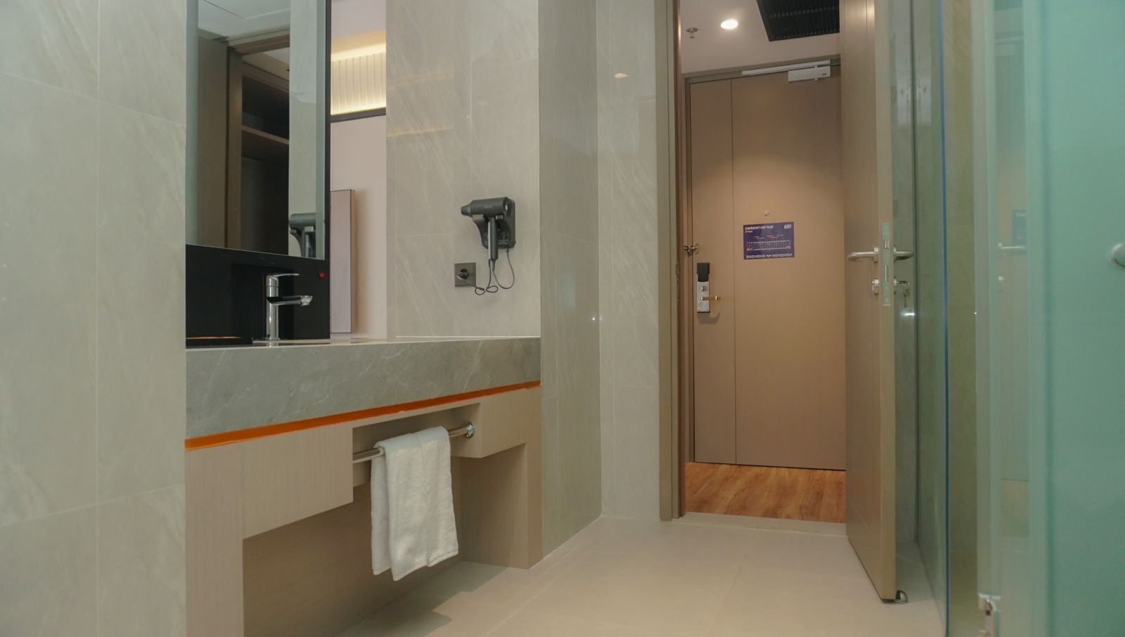 Une salle de bain moderne dotée d’un plan de toilette en marbre, d’un sèche-cheveux et d’un porte-serviettes.