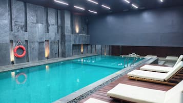 A swimming pool with lounge chairs and a lifebuoy on the wall.