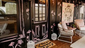 A cozy room with a dark wooden door, a window, wicker furniture, and a welcome mat. - Experience the Magic of Our Original Family Cabin in Tracy City, TN (Tracy City)