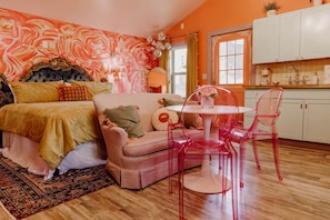 Un dormitorio con cama, sofá, mesa de comedor con sillas, zona de cocina y baño.