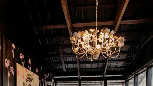 A cozy interior with a chandelier, wicker furniture, and a large window. - Experience the Magic of Our Original Family Cabin in Tracy City, TN (Tracy City)
