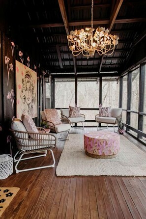A cozy interior with a chandelier, wicker furniture, and a large window.