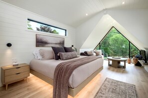 A bedroom with a bed, bedside table, and a large window.