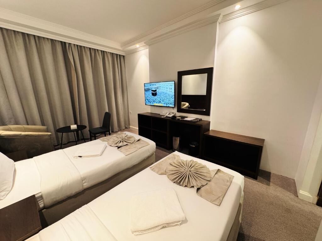 Une chambre d’hôtel avec deux lits, une télévision, un bureau et une chaise.