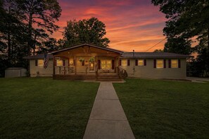 A single-story house with a front porch, a small attached garage, and a well-maintained lawn. - Ultimate Lakefront Cabin with Outdoor Pool in Georgia (Eatonton)