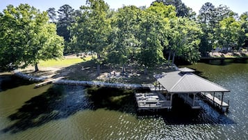 En fastighet vid sjön med en brygga, en överbyggd paviljong och en gräsyta med träd.