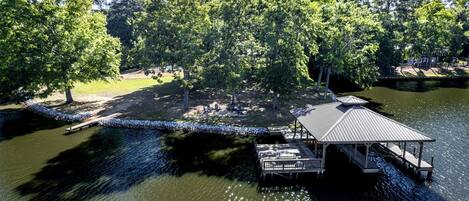 Une propriété située au bord du lac, dotée d’un quai, d’un pavillon couvert et d’une zone herbeuse avec des arbres.