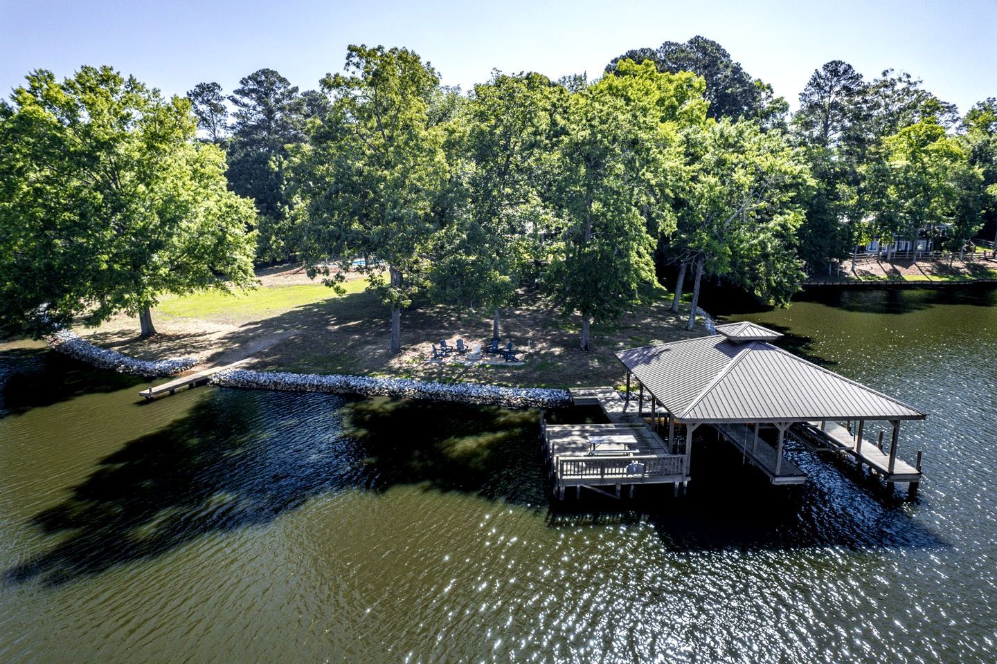 A lakeside property with a dock, a covered pavilion, and a grassy area with trees.